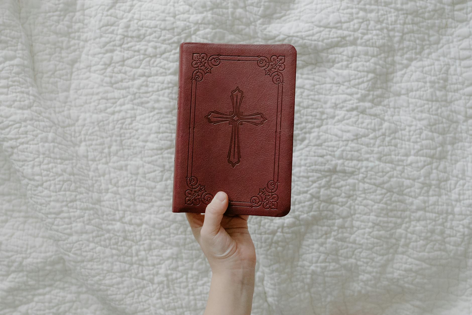 a person holding a bible with a red cover