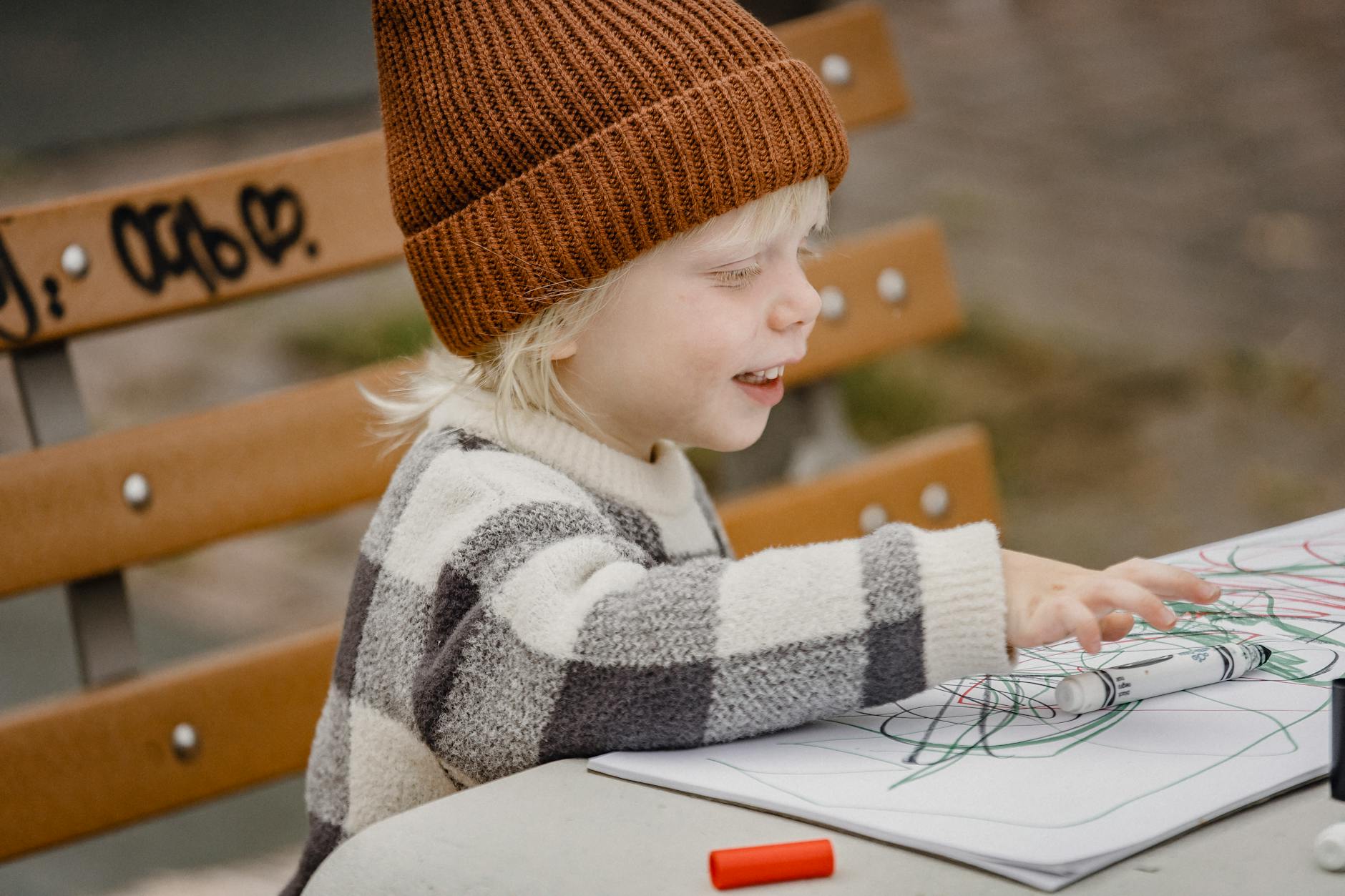 little boy drawing with markers in park