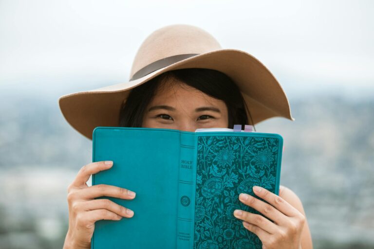 woman with hat holding blue book in hands