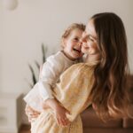 mother carrying her daughter both smiling